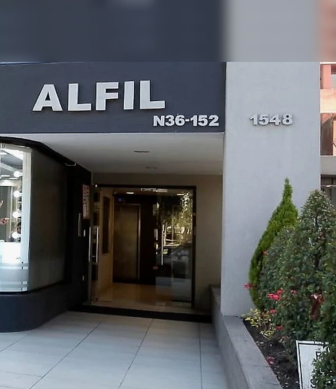 Fachada del Edificio Alfil con el rótulo del edificio y la numeración N36-152, en la Av. Los Shyris de Quito, con el portal de acceso al edificio
